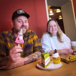 Zwei Mitarbeiterinnen des Cafés sitzen am Tisch mit leckerem Kuchen