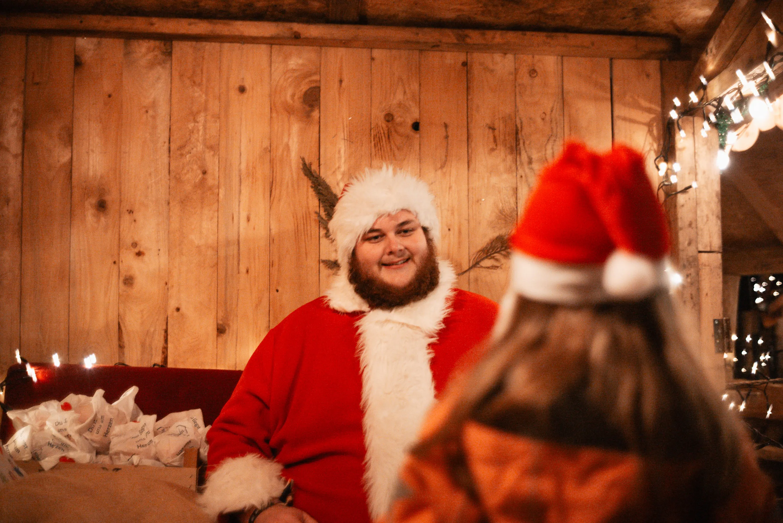 Der Nikolaus hört einem Kind in einer gemütlich beleuchteten Hütte zu.