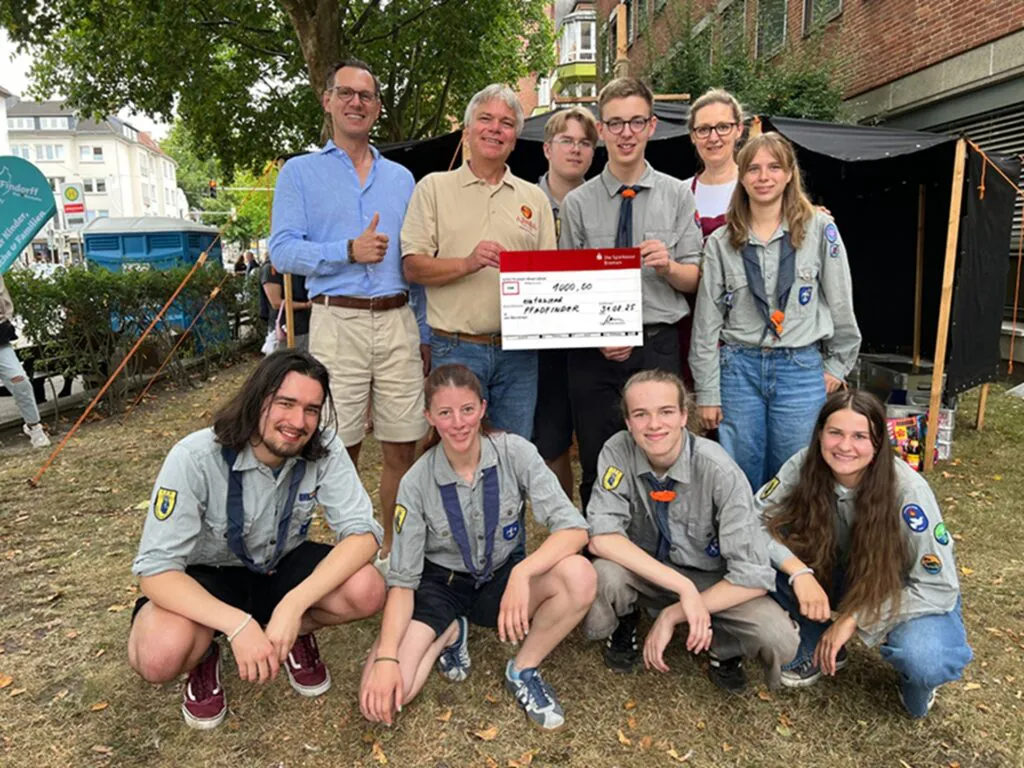 Symbolische Spendenübergabe an Jugendgruppe der Pfadfinder vor ihrem Zelt