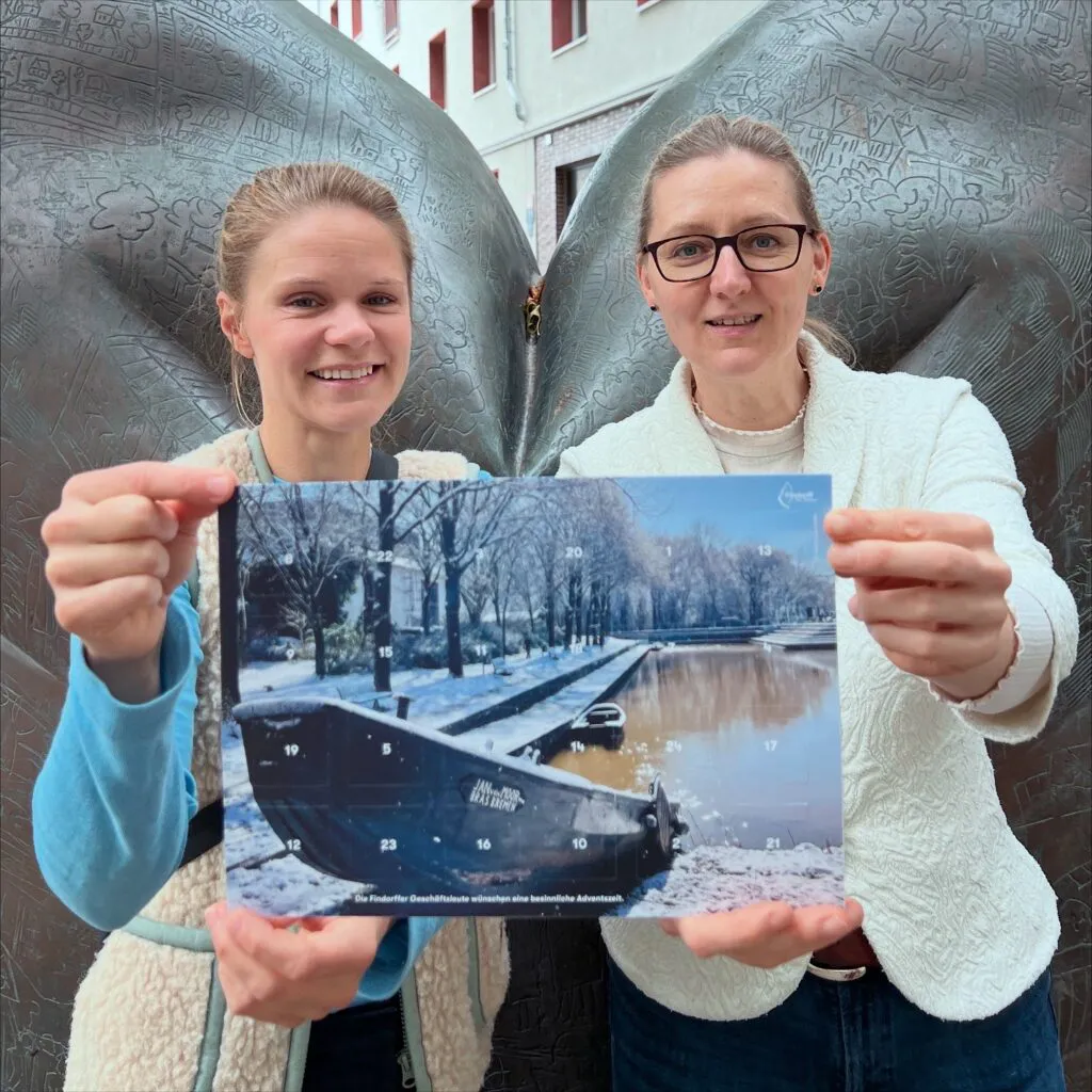 Die Gewinnerin des Fotowettbewerbs und ein Vorstandsmitglied halten den druckfrischen Adventskalender in die Kamera