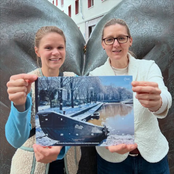 Die Gewinnerin des Fotowettbewerbs und ein Vorstandsmitglied halten den druckfrischen Adventskalender in die Kamera